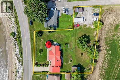 Manicured lawn with mature trees, red-roofed residence, paved driveway, and additional gravel parking area
