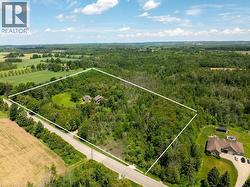 Expansive wooded property with two residences, bordered by a paved road, and surrounded by a rural landscape