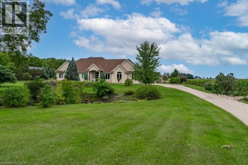 Spacious property featuring a long paved driveway, extensive green lawn, and mature trees