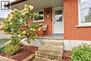 Brick exterior with white trim, concrete steps, and a covered entry