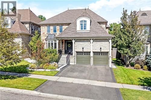 Stone veneer exterior with a prominent dormer window, two-car garage with carriage-style doors, and a stone walkway leading to the entrance