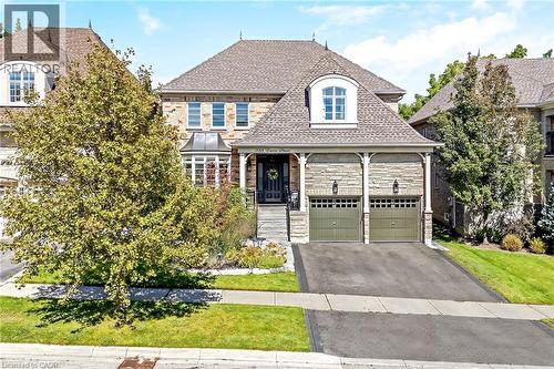 Stone facade with a prominent bay window, dormer roof features, and a two-car garage with arched detailing