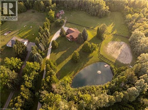 Expansive property featuring a main residence, secondary structure, private pond with a fountain, circular riding arena, and mature tree lines