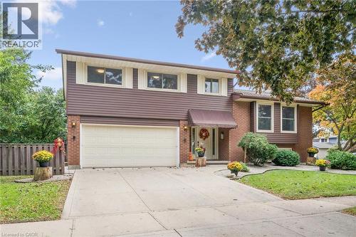 Brick and horizontal siding exterior with a two-car garage, concrete driveway, and mature landscaping