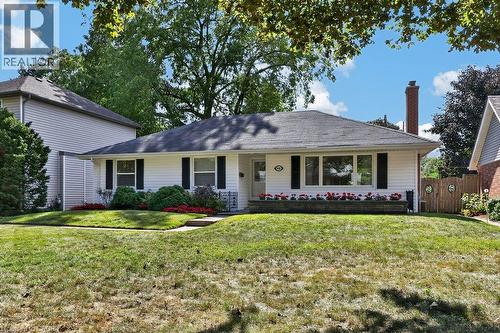 Ranch-style exterior with white siding, a dark shingle roof, and black window shutters