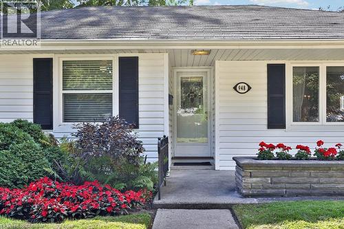 White siding exterior with dark shutters, concrete walkway, and a stone-faced planter box