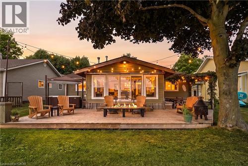 Rear exterior with expansive wood deck, string lighting, and a fire pit