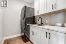 Integrated LG laundry appliances, cabinetry with dark hardware, undermount sink with a black gooseneck faucet, light-toned countertop for folding clothes, engineered hickory floor.