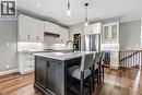 Modern kitchen featuring white shaker-style cabinetry, a dark wood-finish island with seating, stainless steel Samsung Fridge, dishwasher, LG induction stove and LG wine fridge.