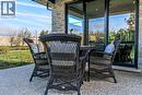 Patio with exposed aggregate concrete flooring, ceiling fan, brick exterior and oversize sliding glass doors
