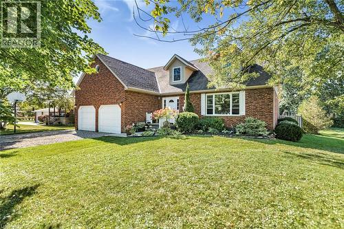 Brick exterior residence featuring a front lawn, attached two-car garage, and established landscaping