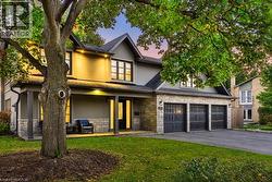 Stone and stucco exterior with a covered front porch, three-car garage, and established landscaping