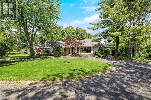Expansive front lawn with mature trees and a paved circular driveway