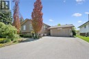 Split-level residence featuring a two-car garage, mature trees, and landscaped garden beds