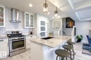 Kitchen featuring pendant lighting, stainless steel range with gas cooktop, wall chimney exhaust hood, white cabinetry, and recessed lighting
