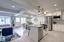 Kitchen featuring appliances with stainless steel finishes, light wood-style flooring, white cabinetry, light stone counters, and beam ceiling