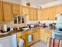 Kitchen featuring white appliances, a textured ceiling, under cabinet range hood, and light brown cabinets