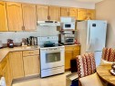 Kitchen featuring white appliances, light countertops, light brown cabinets, under cabinet range hood, and light tile patterned floors