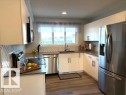 Kitchen with stainless steel appliances, white cabinets, dark wood-style floors,
