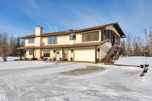View of front of home featuring a garage, a chimney, stucco siding, and stairway