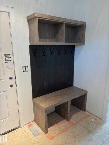 Built-in entryway bench with wood-finish construction, integrated storage cubbies, and a black paneled backboard with five hooks
