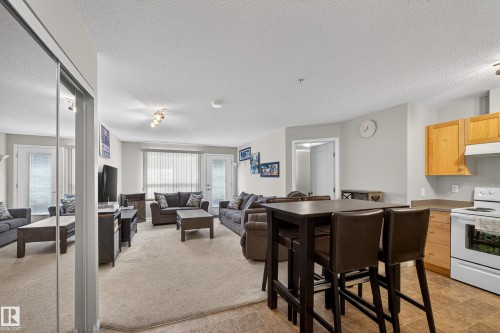 Kitchen featuring white electric range oven, a textured ceiling, light carpet, light countertops, and open floor plan