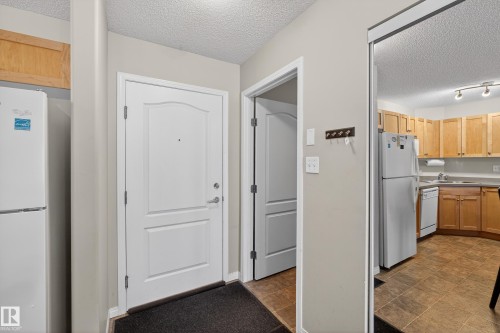 Kitchen with a textured ceiling, white appliances, and light countertops