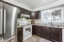 Kitchen featuring white appliances, dark wood finish cabinets, backsplash, light wood finished floors, and light stone countertops