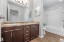 Full bathroom featuring double vanity, shower / bath combination, and light wood-style flooring