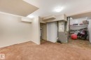 Finished basement featuring heating unit, light carpet, and water heater
