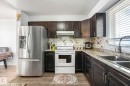 Kitchen featuring white electric range oven, stainless steel fridge, light wood-type flooring, dark wood finish cabinetry, and decorative backsplash