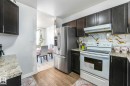 Kitchen with white electric stove, stainless steel refrigerator with ice dispenser, light wood-style flooring, light stone countertops, and backsplash