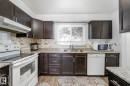 Kitchen with white appliances, dark wood finish cabinetry, light wood finished floors, and backsplash