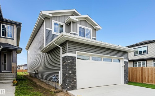 View of front of home with stone siding, board and batten siding, driveway, and a garage