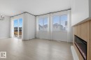 Unfurnished living room featuring light wood-style flooring, a glass covered fireplace, and hanging lights
