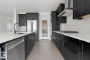 Kitchen featuring dark cabinets, stainless steel appliances, light wood-style floors, light stone counters, and decorative backsplash