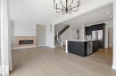Kitchen featuring dark cabinets, open floor plan, a center island with sink, stainless steel appliances, and a glass covered fireplace