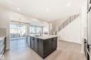 Kitchen featuring a kitchen island with sink, light stone countertops, hanging lights, light wood finished floors, and dishwasher