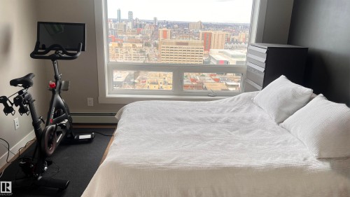 The room features an expansive window providing city views, light-colored walls, and a dark accent wall
