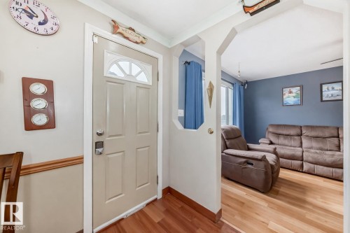 Entryway with hardwood floors and a white door featuring an arched window