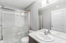 This bathroom features a shower with a sliding glass door, tiled shower surround, a toilet, and a vanity with a white oval sink and a chrome faucet