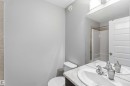 Bathroom featuring a double vanity with two sinks and polished chrome faucets, a toilet, and a shower with beige tiling