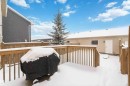 The property features a spacious wooden deck, a mature evergreen tree, and a wooden fence