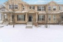 The property features a multi-story exterior with light-colored siding, dark window shutters, and a covered front entry with columns