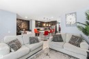 The property features an open-concept living area with light-colored flooring, leading into a kitchen with dark cabinetry and stainless steel appliances