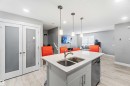 The kitchen features a functional island with a double sink, stainless steel faucet, and a dishwasher