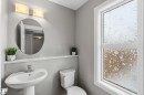 This bathroom features a pedestal sink with a chrome faucet, an oval mirror, and an overhead light fixture with two sconces