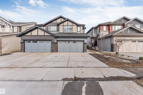 The property features a concrete driveway and two attached garages with light grey doors, offering ample parking