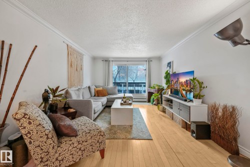 Living area featuring light wood flooring, white walls, and crown molding