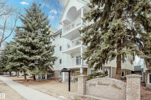 The property is a low-rise building featuring a light-colored facade with white trim and balconies